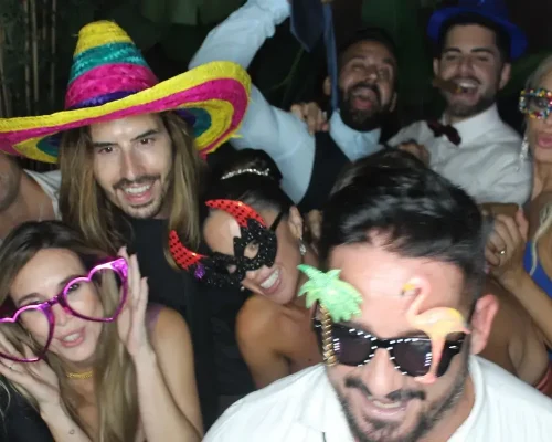 Grupo de amigos durante la celebración de un cumpleaños. Usan gorros, lentes de colores y antifaz | alquiler de fotomatón en Girona